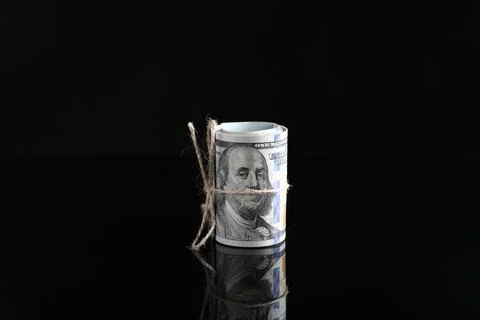 Rolled dollar banknotes with rope on dark mirror surface Stock Photos