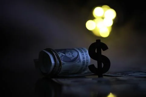Rolled Dollar Bills and Dollar Sign Silhouette with Bokeh Lights in Backgroun Stock Photos