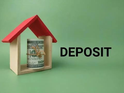 A rolled dollar bundle stands inside a miniature wooden house frame next to.. 库存照片
