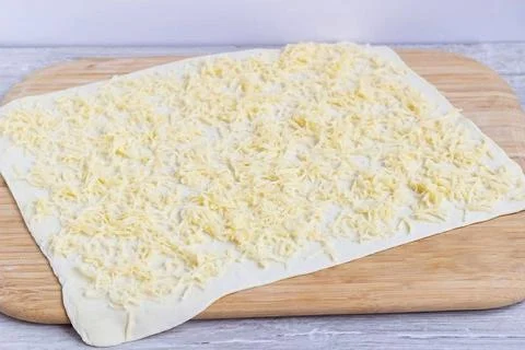 Rolled dough with grated cheese Stock Photos