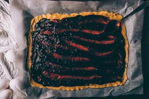 Rolled dough with spreaded currant jam on baking paper Fotos Stock