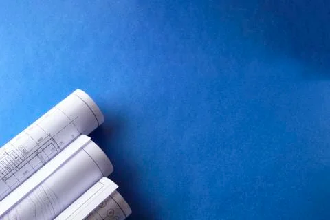Rolled engineering drawings at blue background with copy space Stock Photos