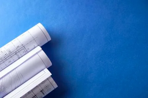 Rolled engineering drawings at blue background with copy space Stock Photos