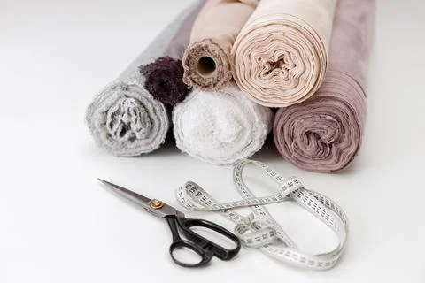 Rolled-up fabric scissors and centimeter on the white seamstress table Foto stock