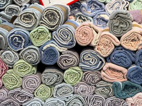 Rolled fabrics with striped patterns stacked in a market stall. Textile, furn Foto stock