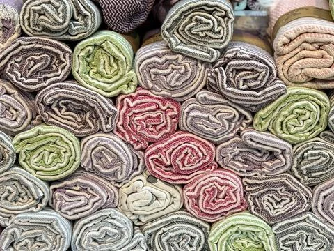 Rolled fabrics with striped patterns stacked in a market stall. Textile, furn Foto stock