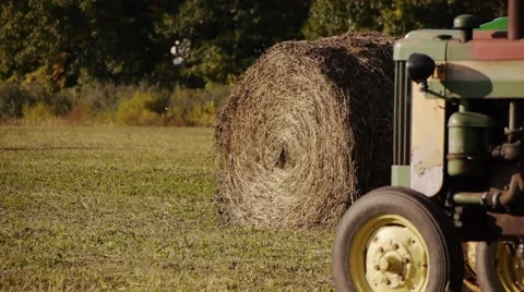 Rolled grass next to an old rusty farm tractor on a hot day. Stock Footage 62438539
