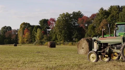 Rolled grass next to an old rusty farm tractor on a hot day. Stock Footage 62438543