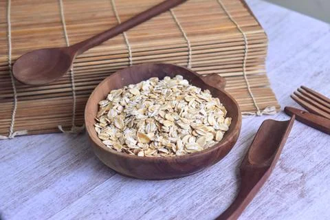 Rolled oats or oat flakes in wooden bowl. Angled view, horizontal. Healthy .. Stock Photos