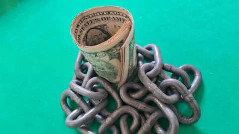Rolled one dollar bill standing inside a heavy metal chain Stock Photos