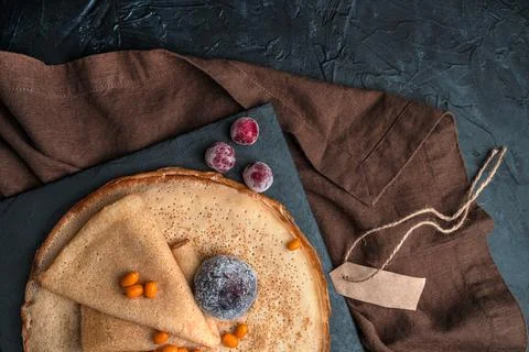 Rolled pancake on a stack of pancakes with berries on a dark background. Stock Photos