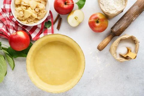 Rolled pie crust in a baking dish with tools and ingredients. Stock Photos