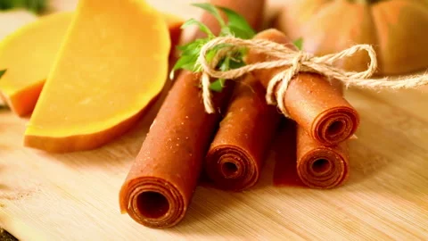 Rolled pumpkin pastila with herbs and pumpkin on wooden background Stock Footage 346547882