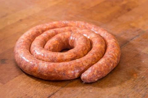 Rolled raw red sausage on the table Stock Photos