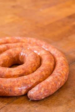 Rolled raw red sausage on the table Stock Photos