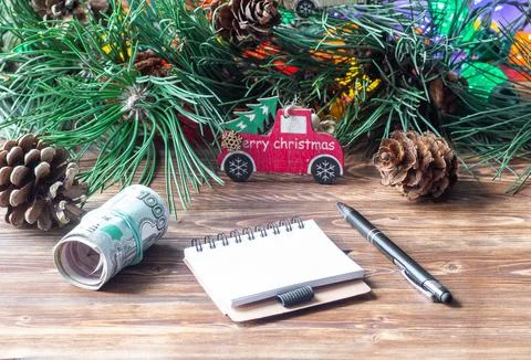 Rolled Russian ruble banknotes, a blank notebook, and a pen on a wooden table Foto stock