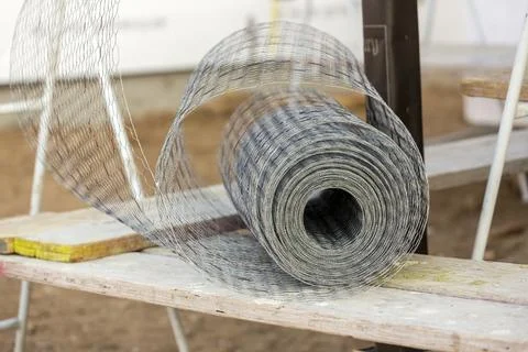 Rolled up silver construction mesh sitting on scaffolding at a construction s Stock Photos