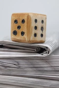Rolled up stack of fresh newspapers and wooden dice, news, printed background Stock Photos