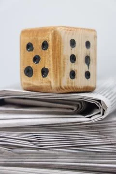 Rolled up stack of fresh newspapers and wooden dice, news, printed background Stock Photos