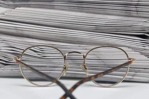 Rolled up stack of fresh newspapers and glasses, news, printed background. Stock Photos