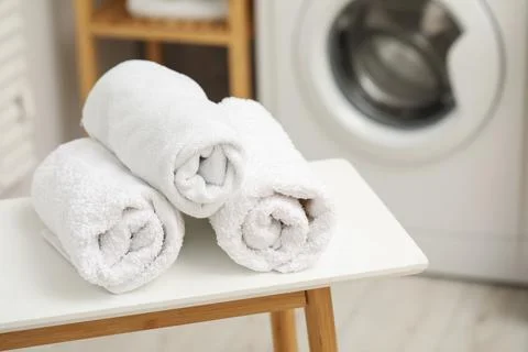 Rolled terry towels on white table in laundry room. Space for text Stock Photos