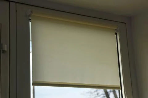 Rolled textile blinds on a plastic window in a room. Stock Photos