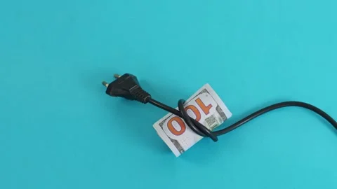Rolled US hundred dollar bill tied with black electric power plug on background Stock Footage 332054659