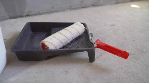 Roller in the bathroom with putty. Man preparing to paint a wall dipping a pa Stock Photos