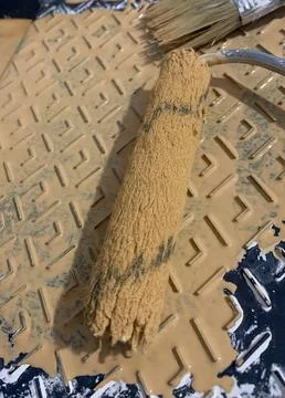 A roller in beige paint on a stand for rolling out paint Foto stock