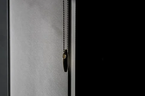 Roller blind beaded chain hanging against a textured fabric Stock Photos