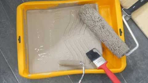 Roller brushes and paintbrush lie in special yellow tray Stock Footage 124299451