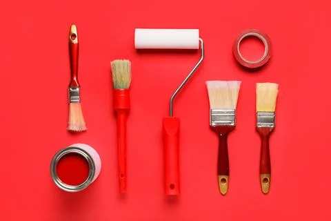 Roller with can of paint, different brushes and adhesive tape roll on red bac Stock-Fotos