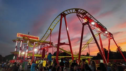 Roller coaster attraction moving at an amusement park during a beautiful sunset Stock Footage 344470397