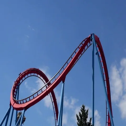 Roller coaster halfloop with cars passing on an amusement park with blue sky Vídeos de archivo 69734447