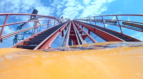 Roller coaster rolling up tracks toward cloudy blue sky Video stock 66544423