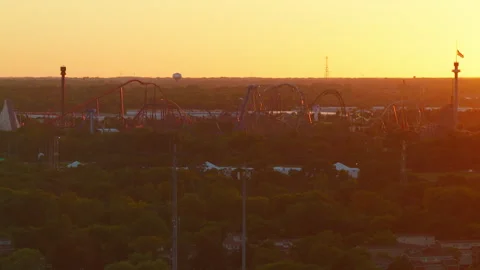 Roller Coaster Skyline Burns Orange as the Last Sun Drops Behind the Treeline Stock Footage 345999544