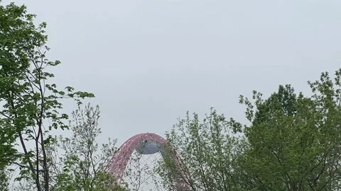 Roller coaster track peeking through lush green trees under grey sky, ideal.. Stock Footage 341267019