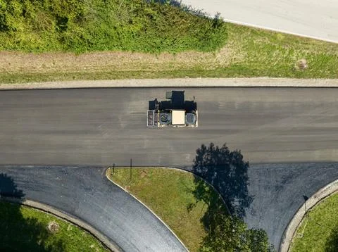 Roller compacting asphalt on a road construction site from above, aerial. Stock Photos