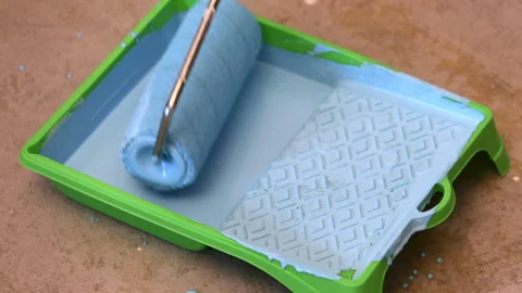 The roller is dipped in blue paint and rolled out in a cuvette Stock Footage 113788515