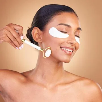 Roller, eye patch and beauty with Indian woman in studio for facial, spa Fotos de archivo