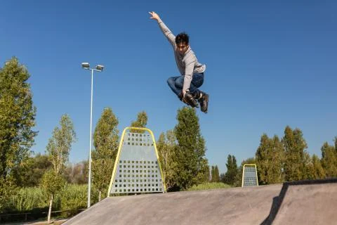 Roller guy does a trick in the air in a skate park Stock Photos