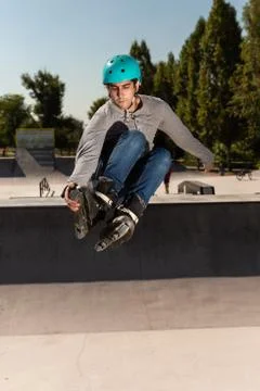 Roller guy does a trick in the air in a skate park Stock Photos