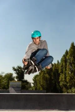 Roller guy does a trick in the air in a skate park Stock Photos