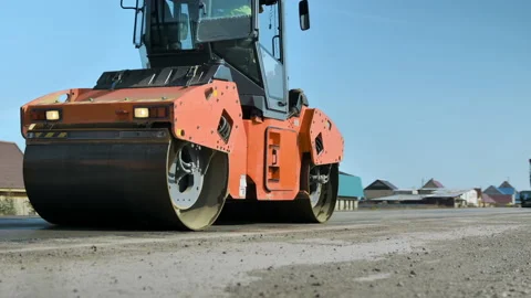 The roller levels and compacts the asphalt against the blue sky. A layer of Stock-Footage 140104619