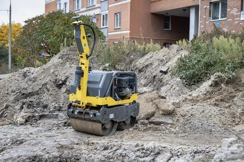 A roller machine is being used in a building site to flatten the ground. Tree Stock Photos