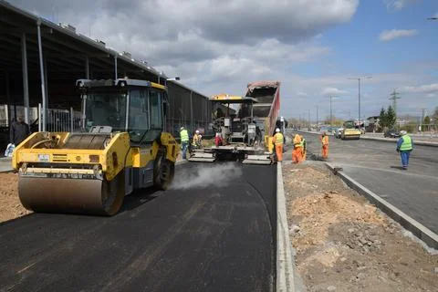 Roller machine compressing the asphalt behind the paver Stock Photos