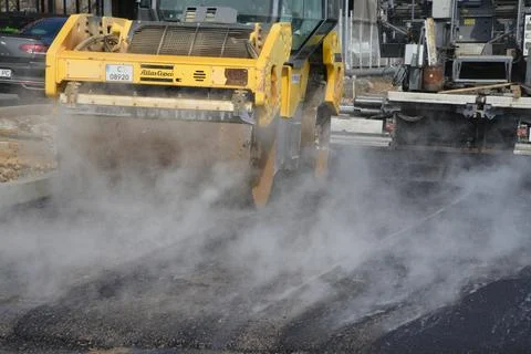 Roller machine compressing the asphalt behind the paver Foto stock
