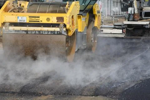 Roller machine compressing the asphalt behind the paver Foto stock
