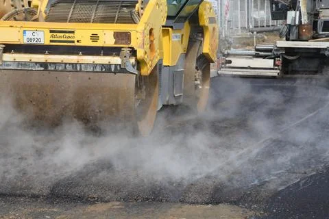 Roller machine compressing the asphalt behind the paver Stock Photos