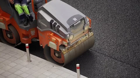 Roller machine compressing newly laid asphalt during road paving operations. Video stock 314134366